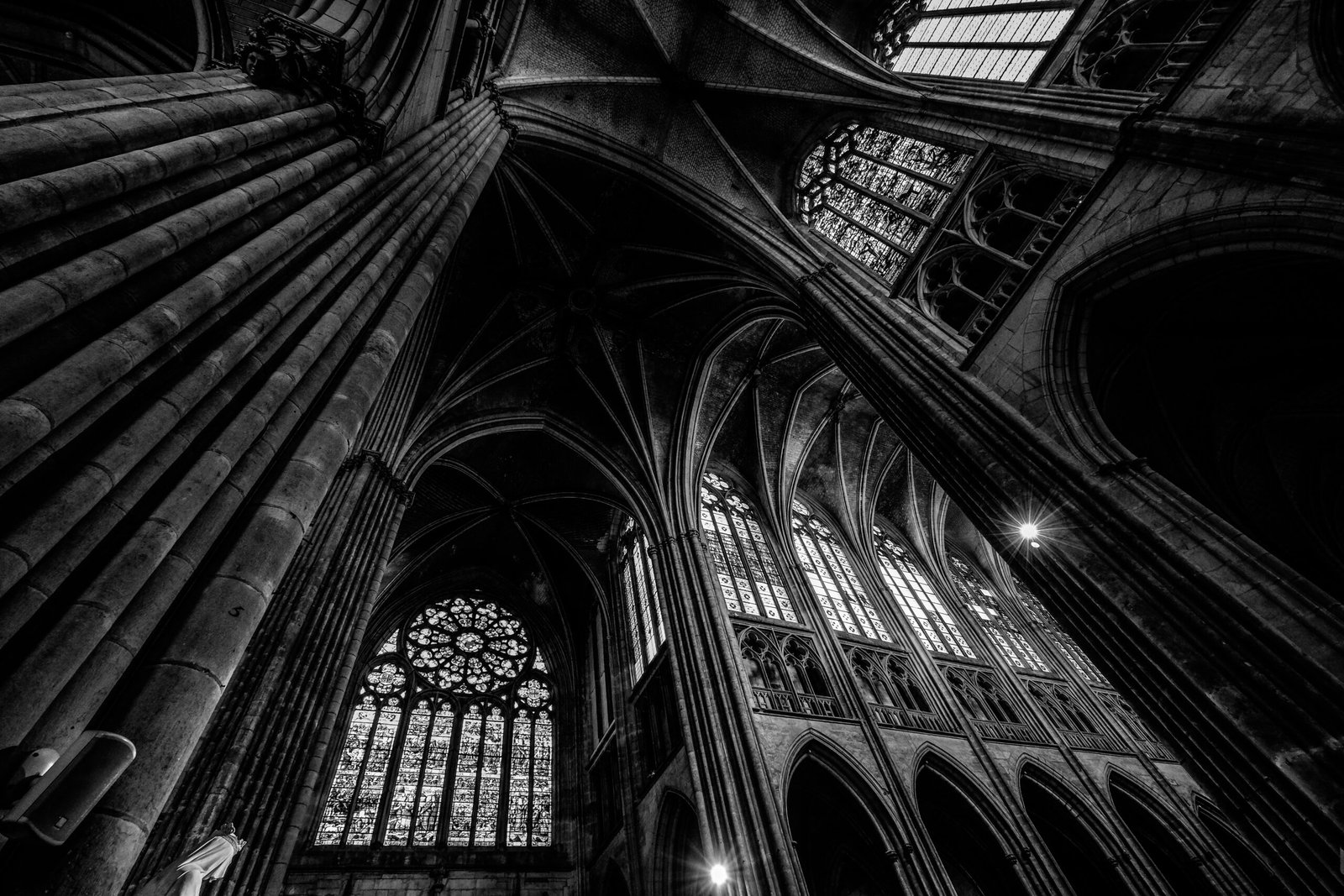A low angle shot of a cathedral ceiling with windows in black and white